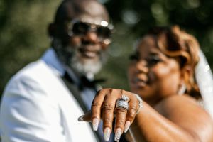 Close-up shot showcasing elegant wedding rings with couple in background.