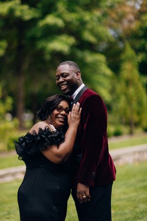 Joyful couple embracing and laughing together during outdoor formal photoshoot.