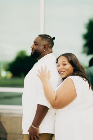 A loving couple in white embraces while sharing a tender moment outdoors.