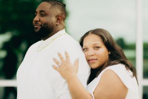 A couple shares a joyful moment outdoors in matching white outfits.