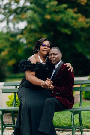 Happy couple shares tender moment while sitting together on park bench outdoors.