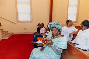 Wedding guests in traditional attire seated in church pews during a ceremony.