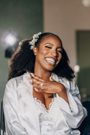 A joyful moment captured in white lace and satin with natural curls and radiant smile showing pure happiness.