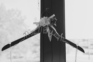 Black hangers and clothes hanging neatly on a white wall with soft shadows creating a minimalist aesthetic.
