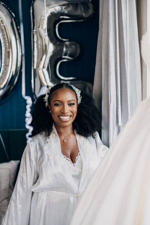 A wedding dress display with white gowns and veils hanging in a bridal boutique.