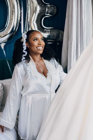 A bride in white getting ready while holding flowing fabric from her wedding gown.