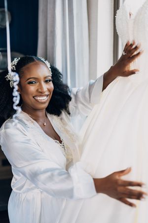 Series of artistic preparation shots showing a white satin robe and wedding dress details.
