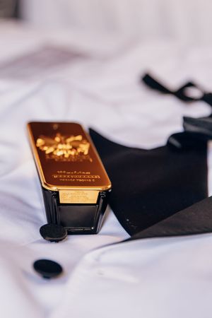 A luxury fragrance bottle with gold detailing against white fabric.