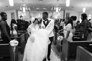 Black and white photo of a wedding ceremony exit in a church aisle.