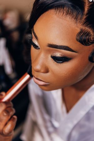 Close-up of bridal makeup application showing glamorous eye shadow and perfect brows.