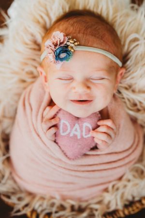 Newborn baby wrapped in pink fabric with decorative text and accessories. Annapolis newborn photography studio