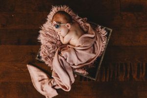 Sleeping newborn on pink fabric against dark wooden background. Annapolis newborn photographer