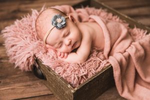 Newborn baby sleeping peacefully on soft pink fur blanket against wooden background. Annapolis Newborn photography