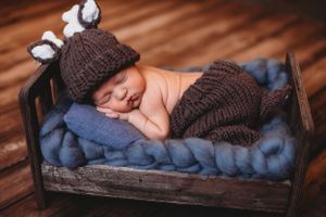 Cozy newborn photography setup with baby sleeping on blue blanket and wooden backdrop. Annapolis newborn photographer