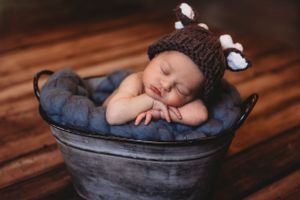 Professional newborn photo with baby sleeping in gray basket on wooden floor. Annapolis newborn photographer