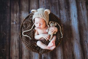 Artistic newborn photography with baby lying on rustic wooden floor wearing a knit hat. Annapolis newborn photographer