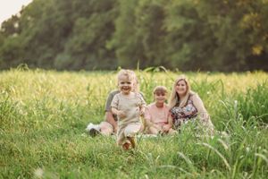 A family enjoys a casual moment together sitting in tall summer grass.
