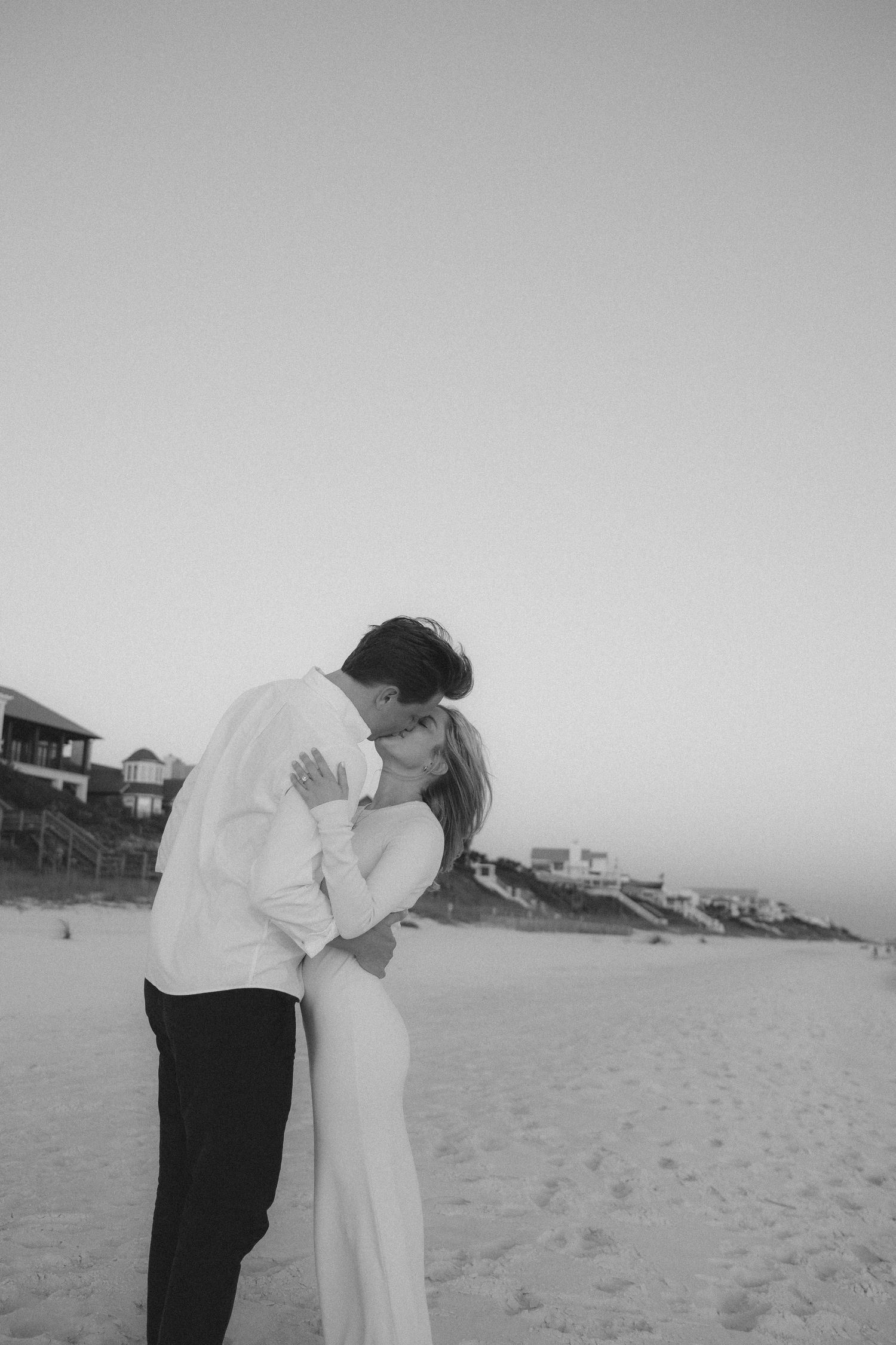 Romantic couple embracing on a serene beach at dusk.