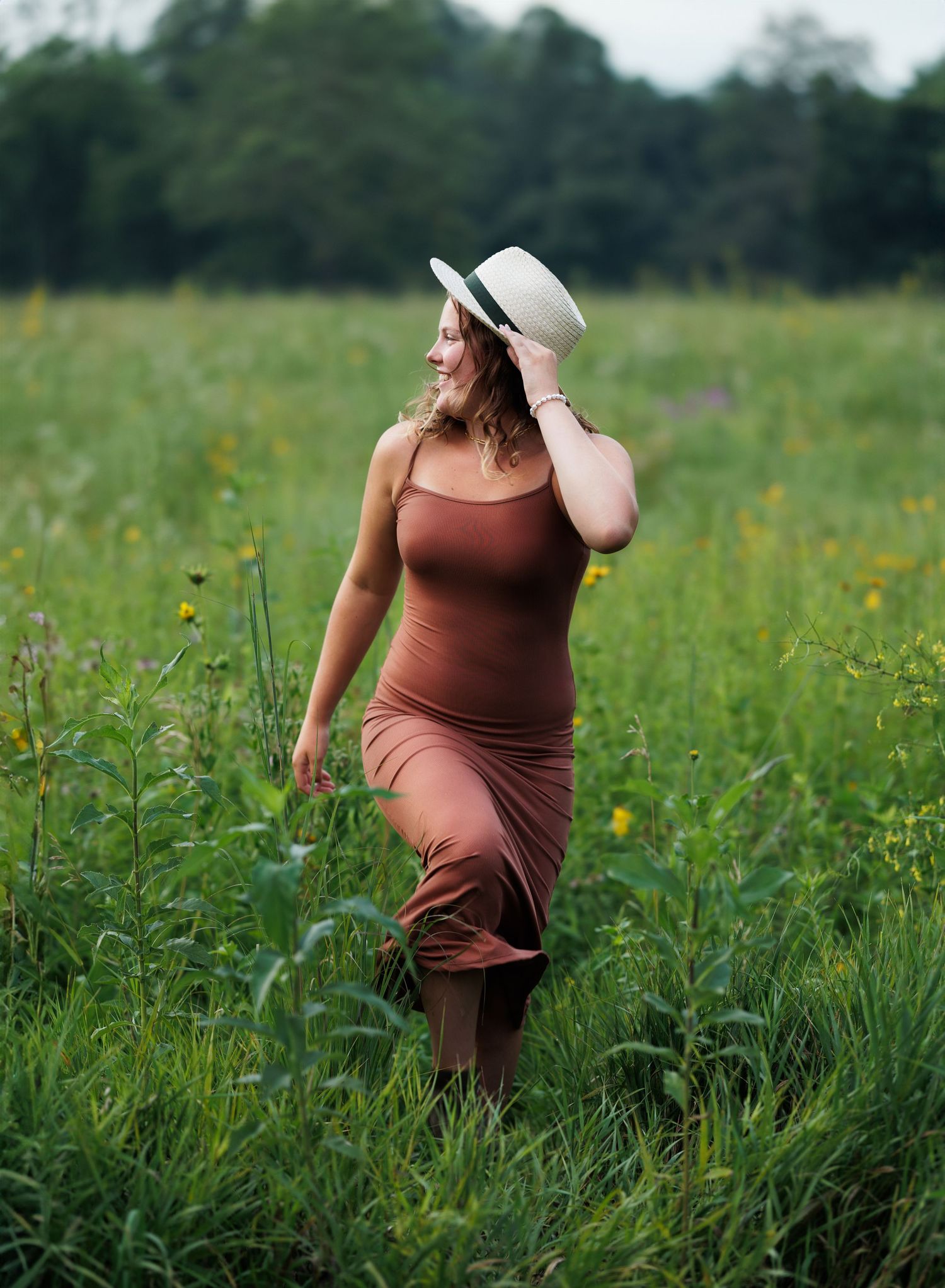 A flowing blue dress creates movement in a snowy winter landscape during a maternity photoshoot.