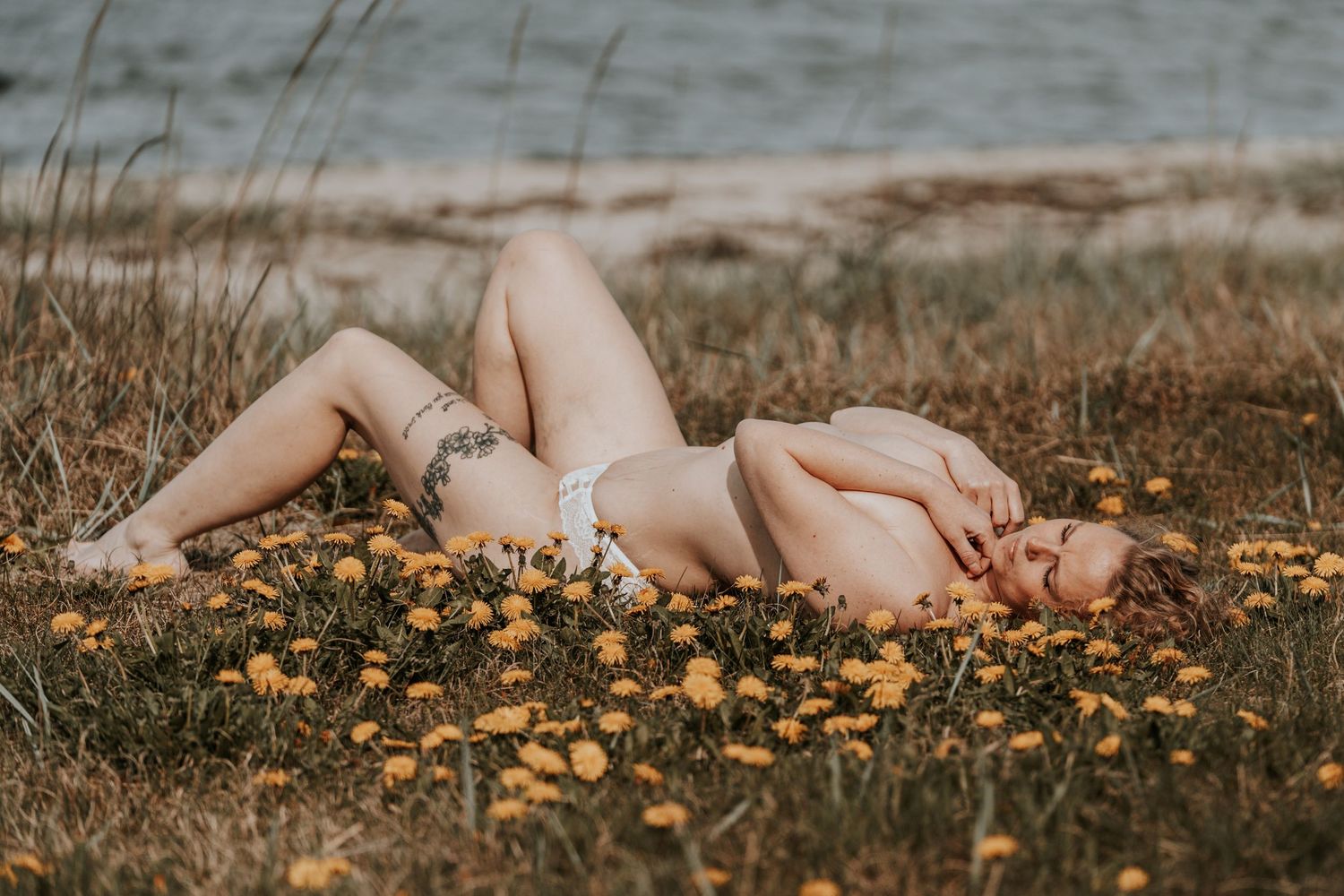 Kunstnerisk udendørs boudoir-portræt af en person liggende i naturen blandt blomster – fotograferet af CHH_foto i Jægerspris, Frederikssund