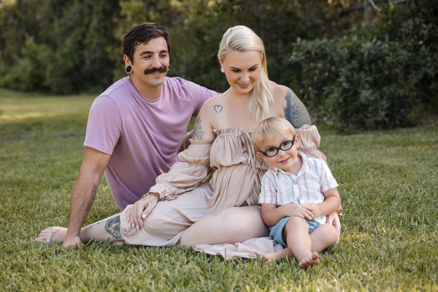 Joyful maternity moment with couple and toddler son during outdoor photo session.