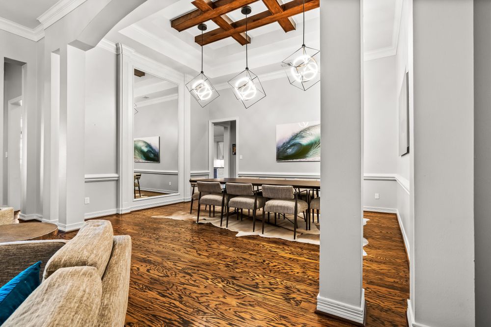 Modern dining space with wooden beam ceiling, geometric light fixtures, and hardwood floors.