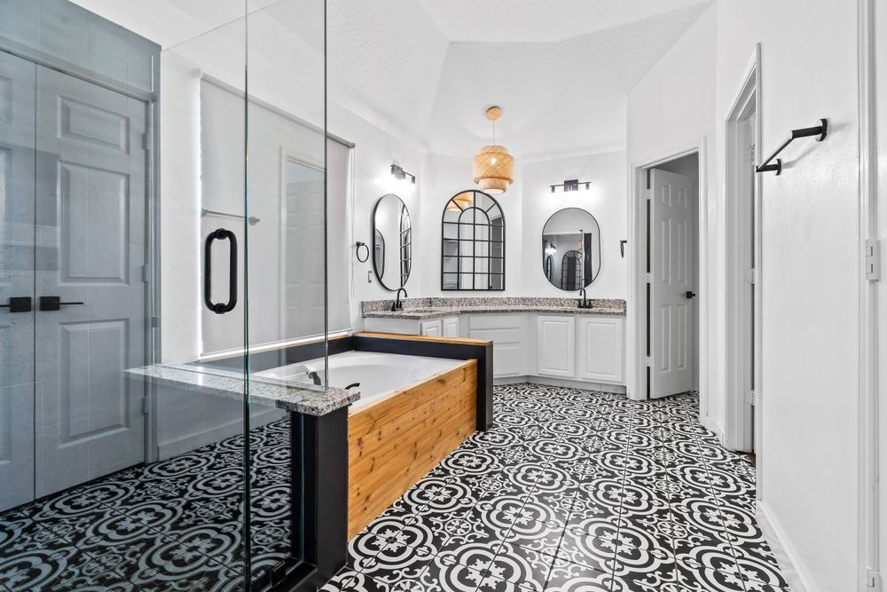 Modern bathroom interior with geometric black and white floor tiles, wooden vanity, and arched mirrors on white walls.