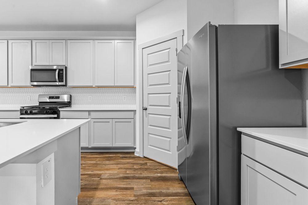 Modern white kitchen with stainless steel appliances, hardwood floors and center island featuring clean lines and ample storage.