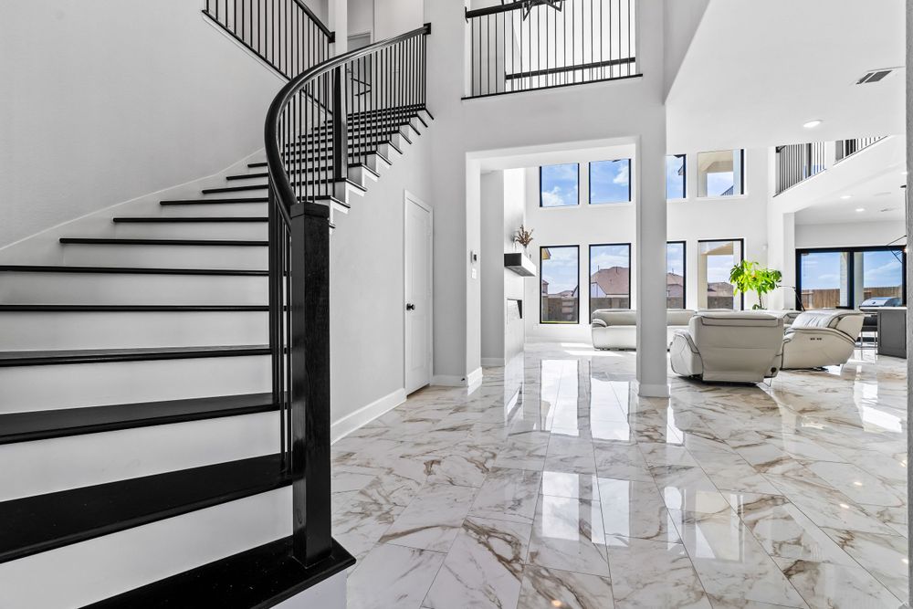 Luxurious modern home interior with spiral staircase, marble floors and bright living room featuring panoramic windows.