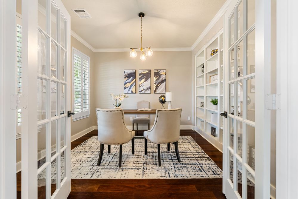 Modern dining room with French doors, built-in cabinets, geometric rug, and elegant chandelier.