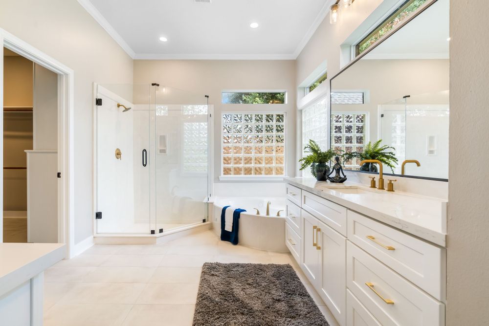 Spacious master bathroom with glass shower, white vanity, and large mirrors.