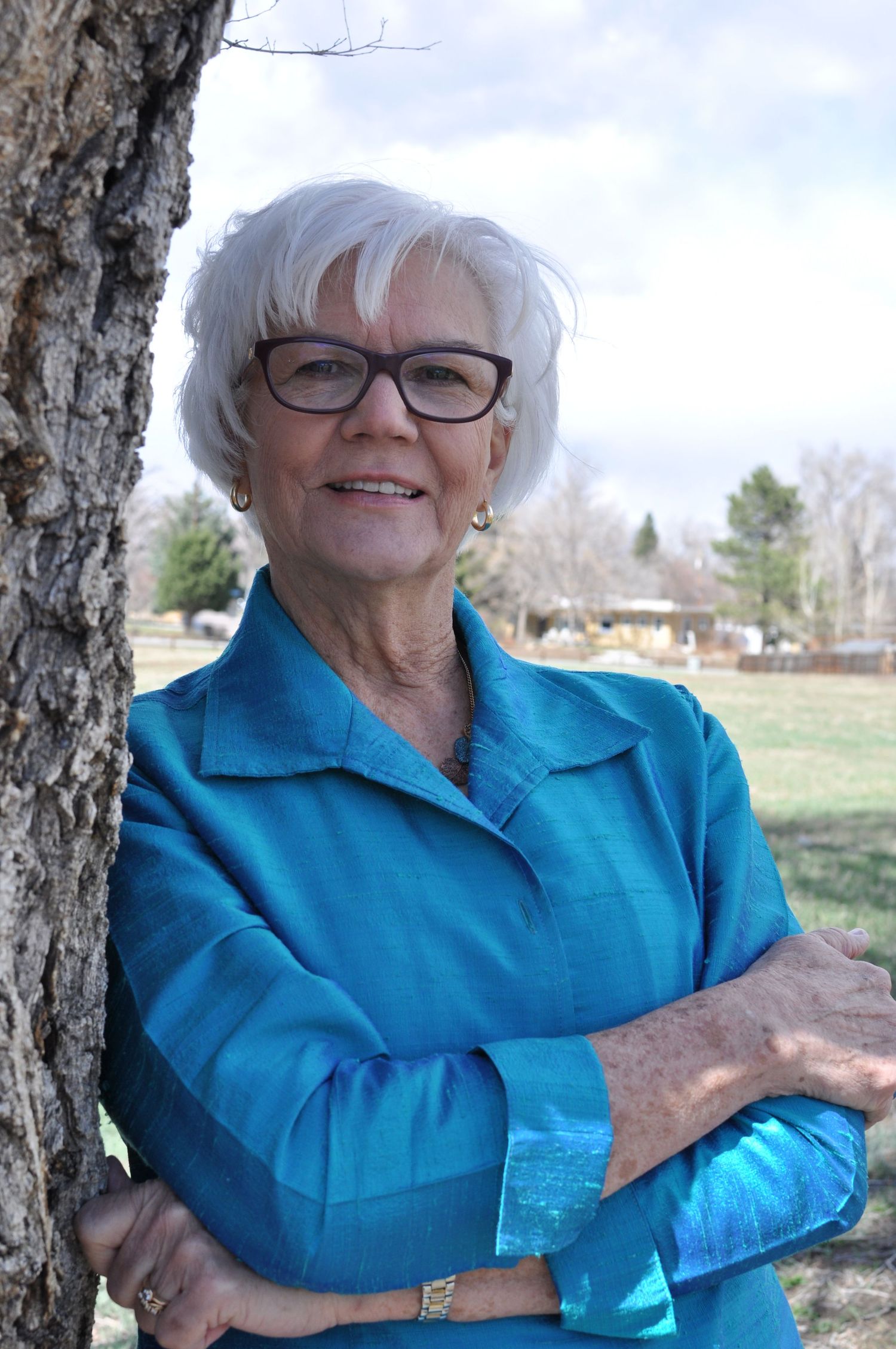 A gray-haired lady with glasses poses for her headshot