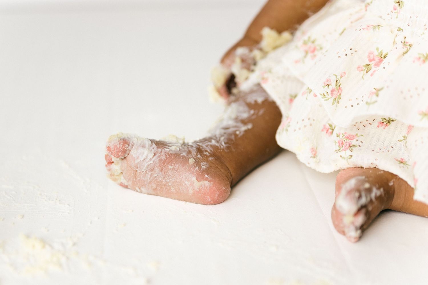 Baby's feet covered in white powdery baking flour mess while cooking or playing.
