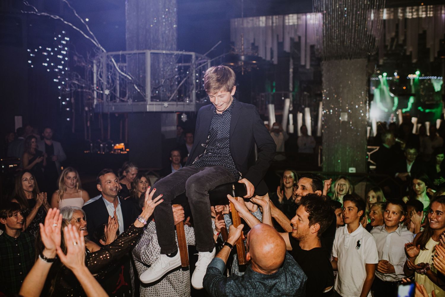Boy getting lifted up in a chair during his Bar Mitzvah in San Diego