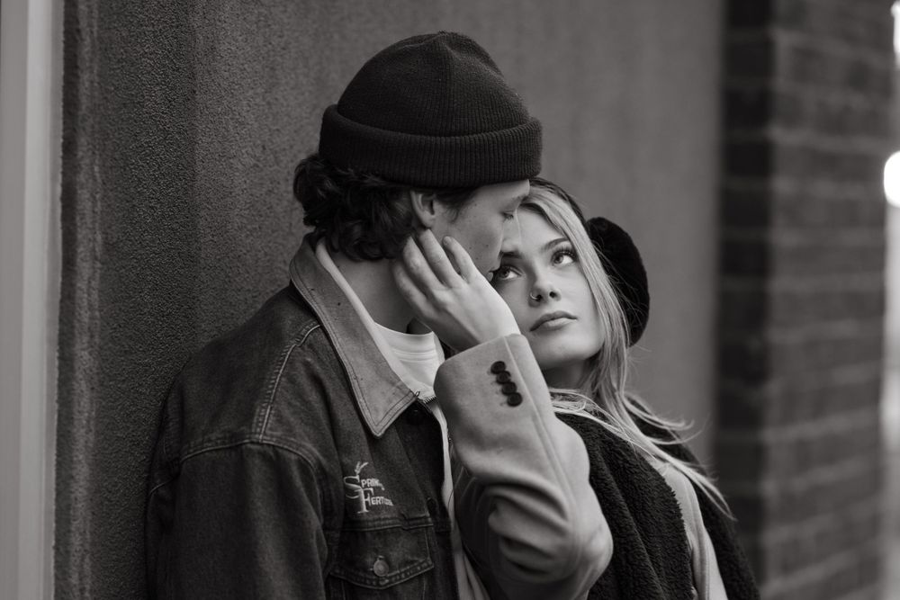An intimate black and white portrait of a couple in winter attire.
