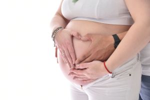 Close-up details of a pregnant belly with hands gently cradling the bump.