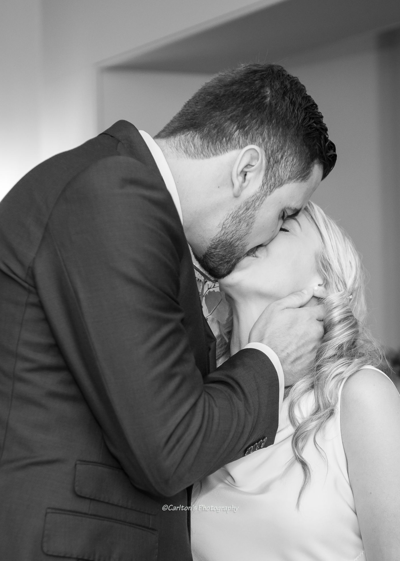 Intimate black and white portrait of newlyweds sharing their first kiss.