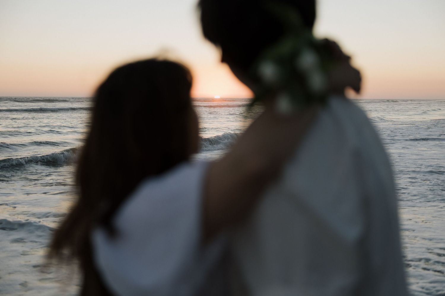 engaged couple looking off to the sunset