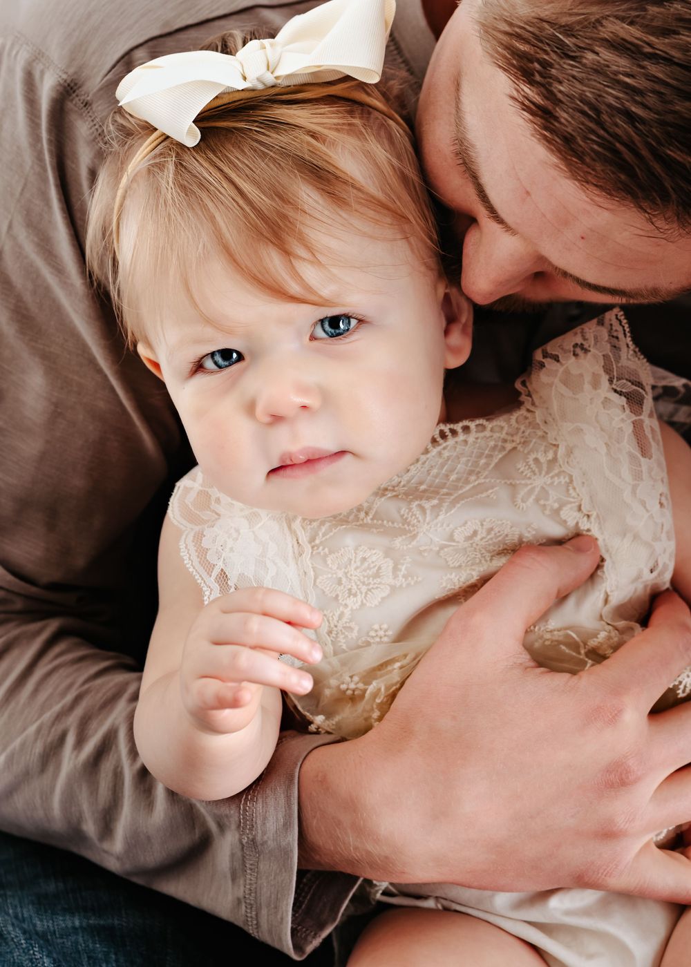 A series of candid photographs showing a child in a lace dress lying on brown bedding.