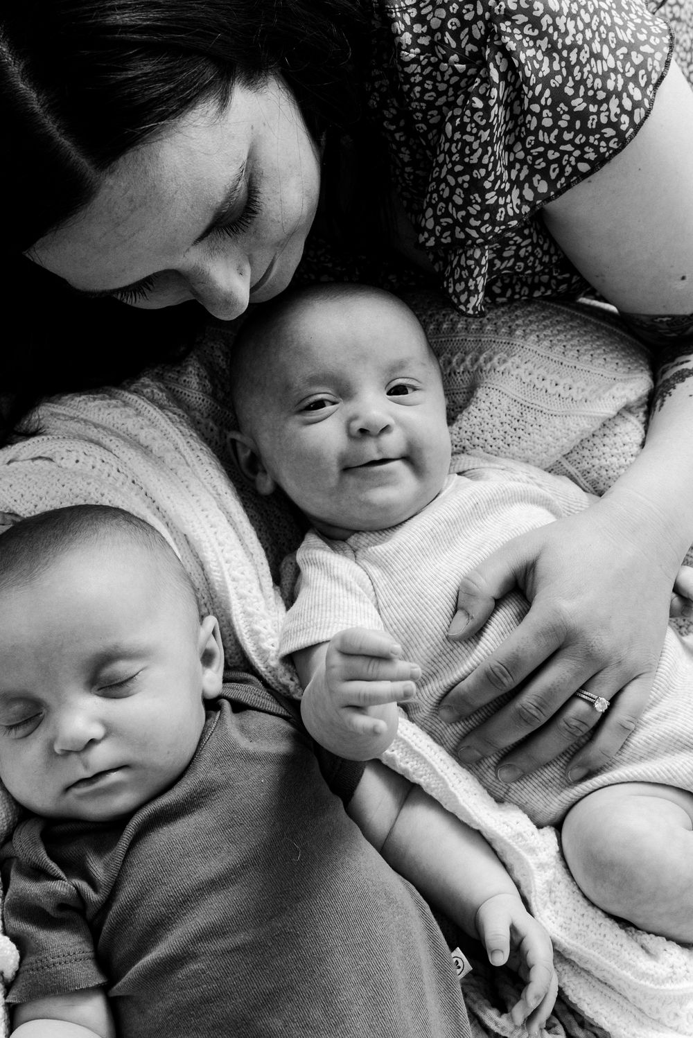A series of black and white photos showing tender moments between a caregiver and infant in various poses.