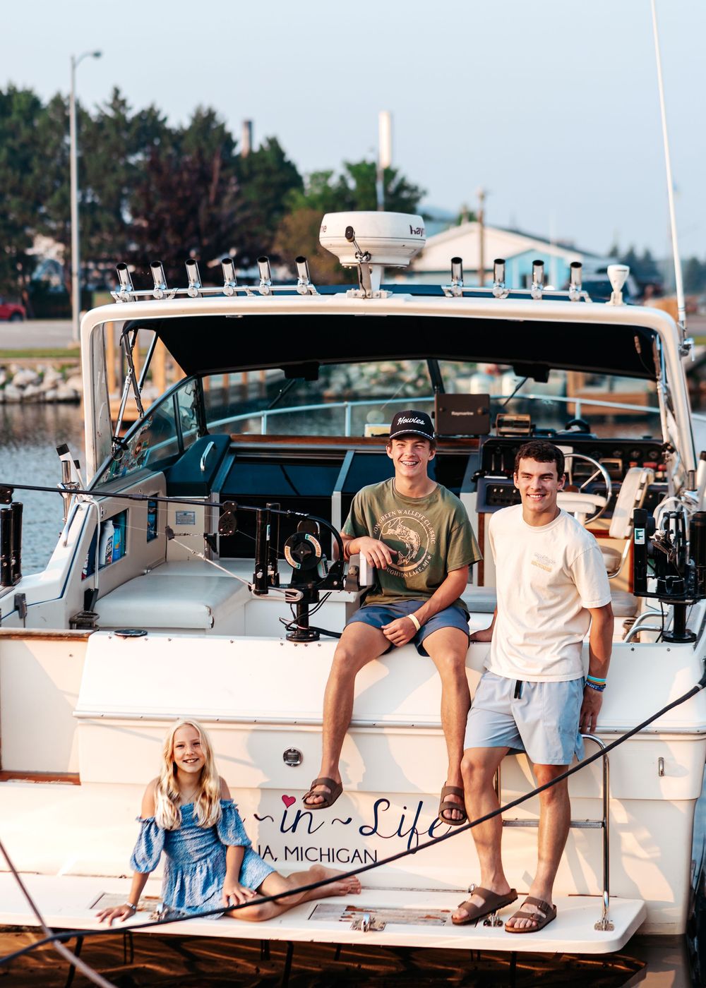 Group relaxing on a white fishing boat named "Li'l" docked at a marina on a sunny summer day.