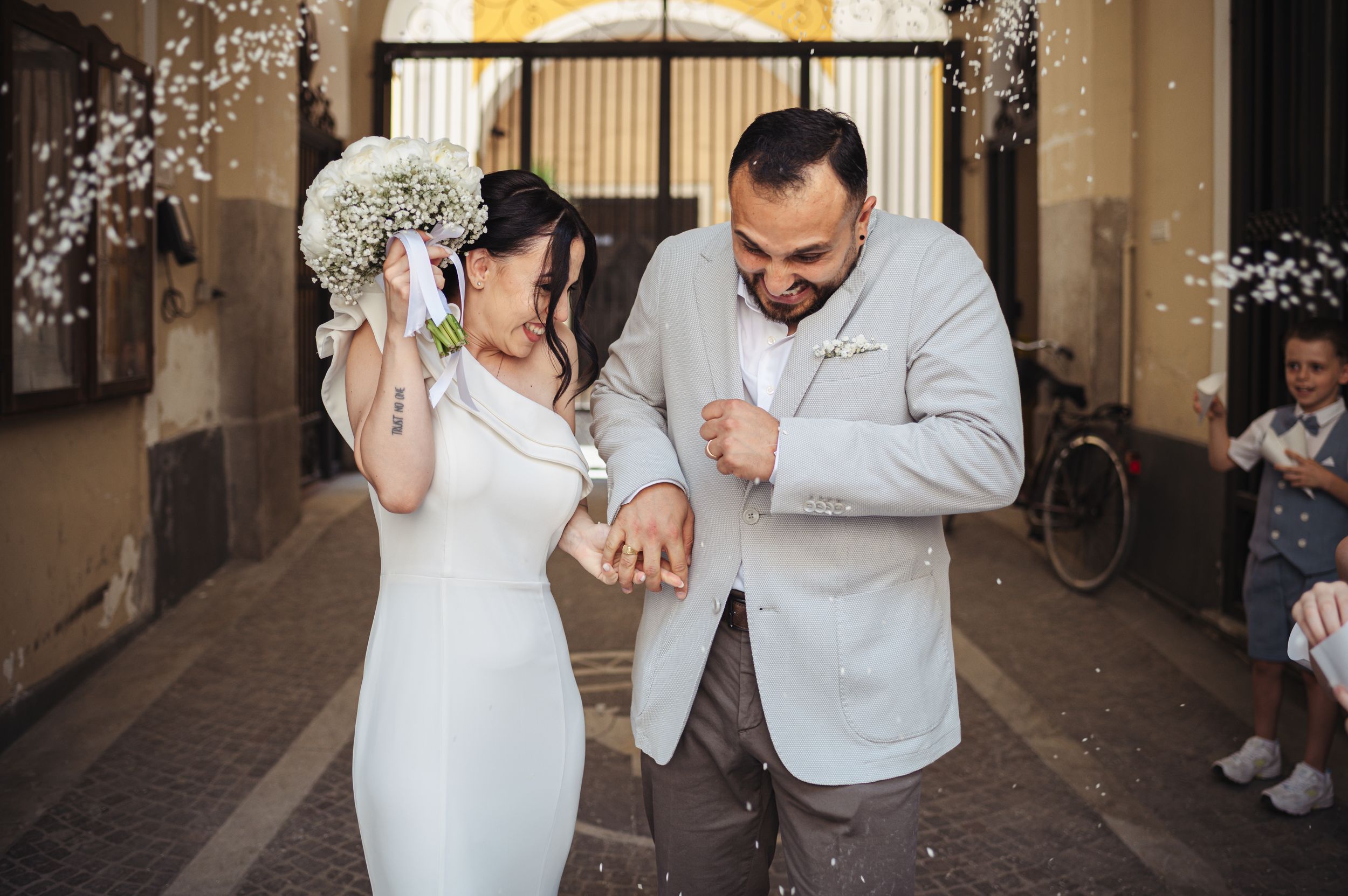 Two people look at their watches on a wedding day in a spacious indoor venue decorated with twinkle lights.