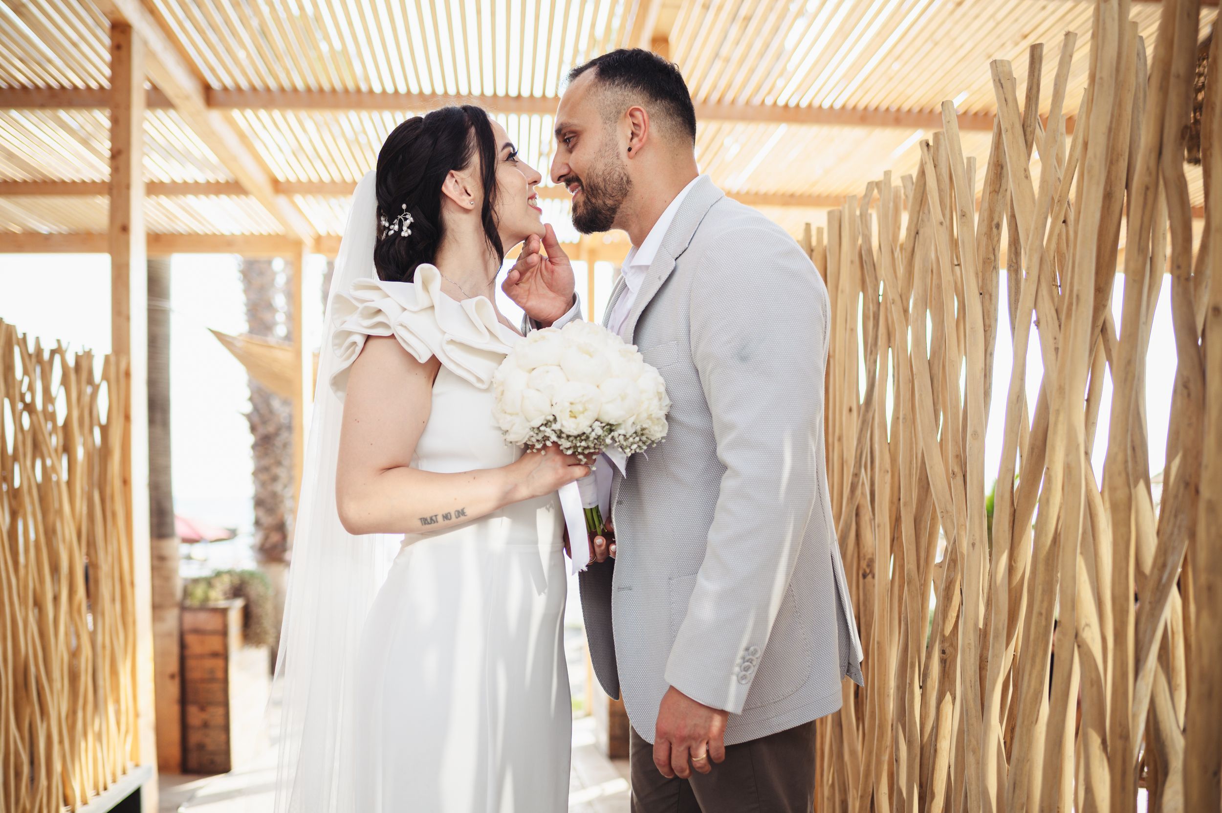 A romantic wedding couple shares tender moments in a rustic bamboo-walled setting during their celebration.