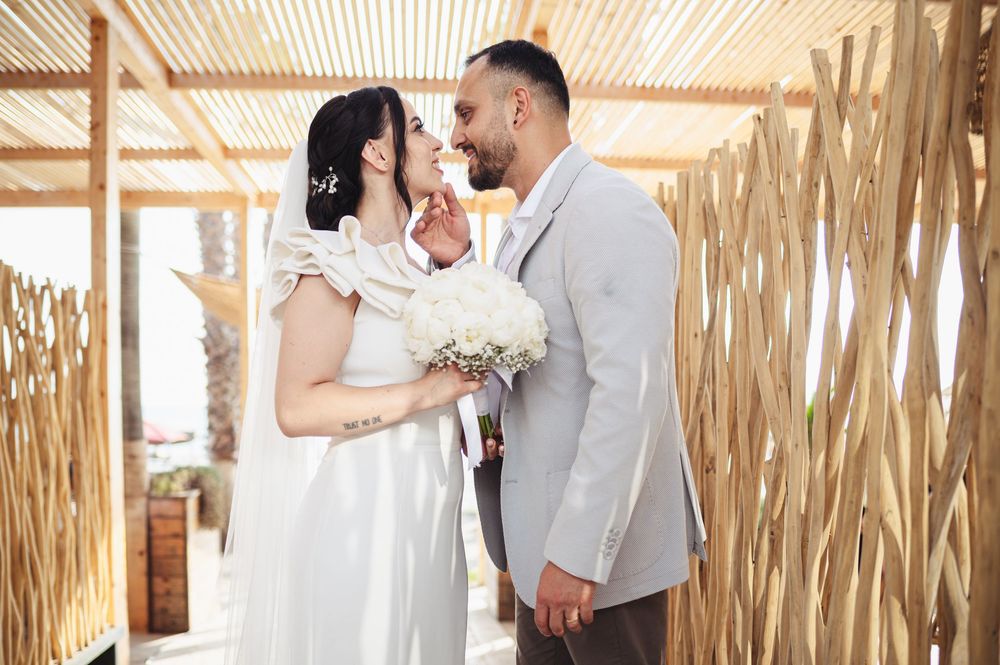 A romantic wedding couple shares tender moments in a rustic bamboo-walled setting during their celebration.