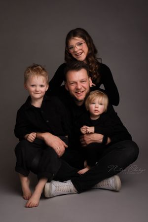 Vader met kinderen in zwarte kleding tijdens familie fotoshoot in studio, Zeeland