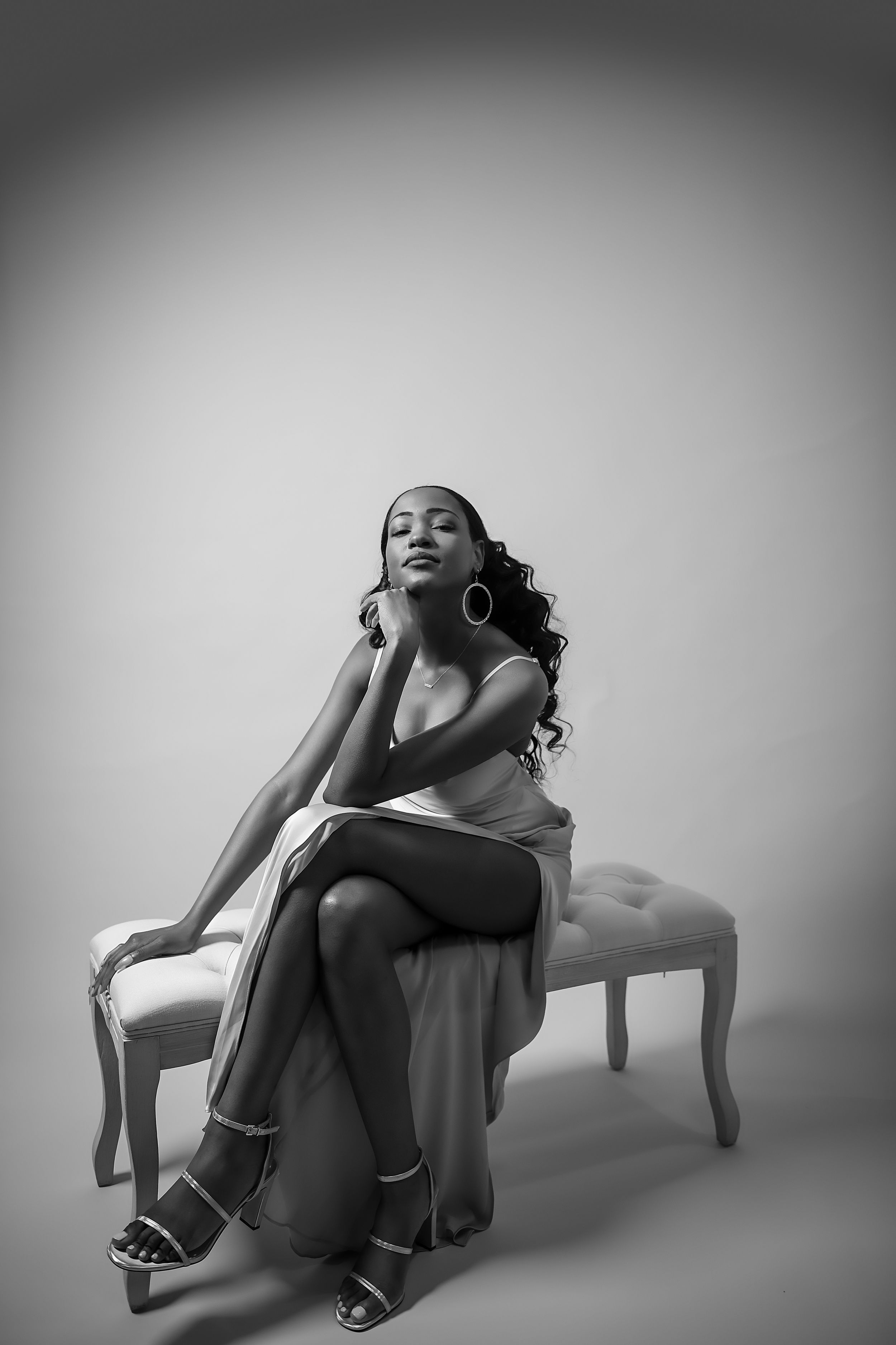 Glamorous black and white portrait of model posing elegantly on vintage bench.