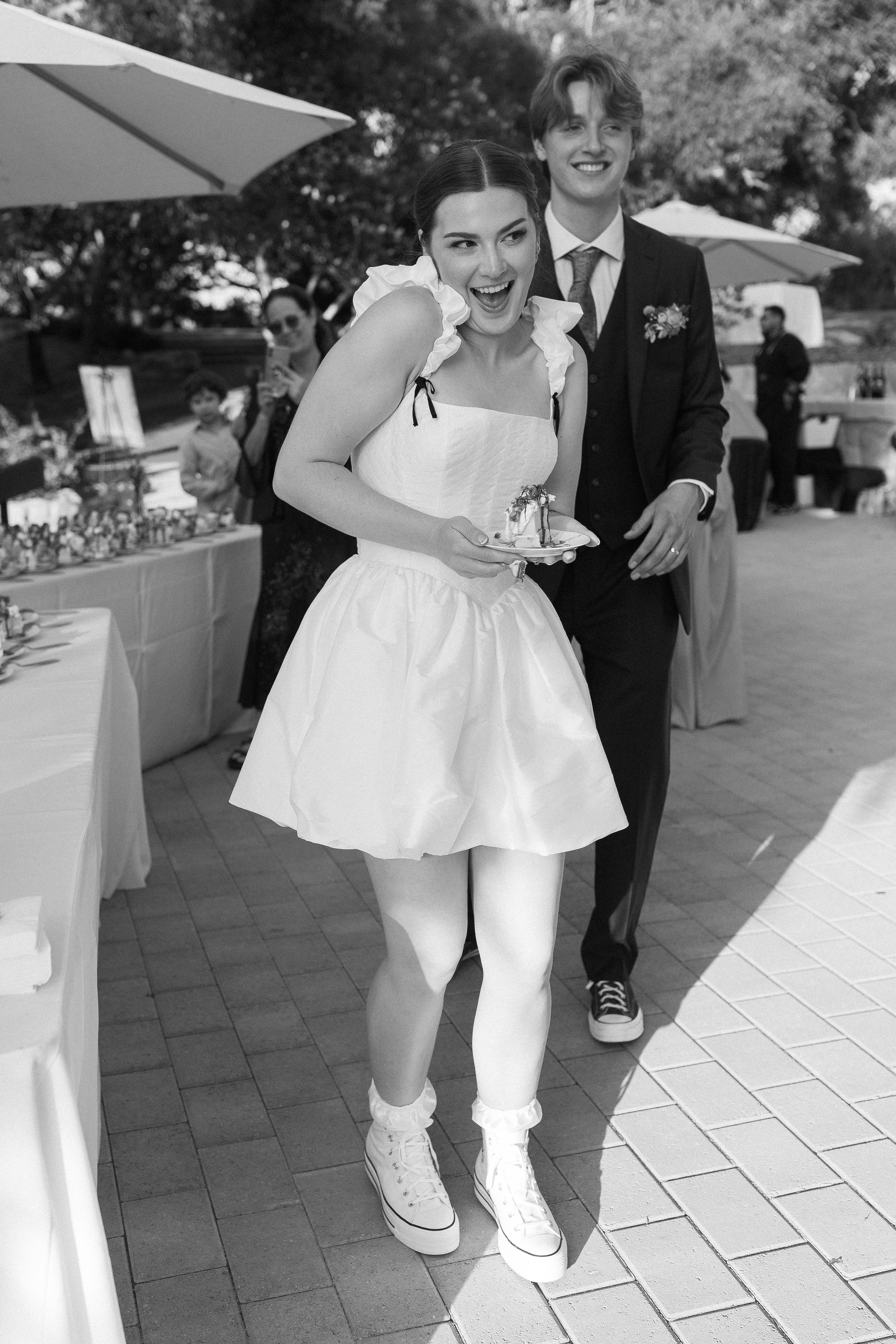 documentary candid black and white photo of a bride holding her wedding cake