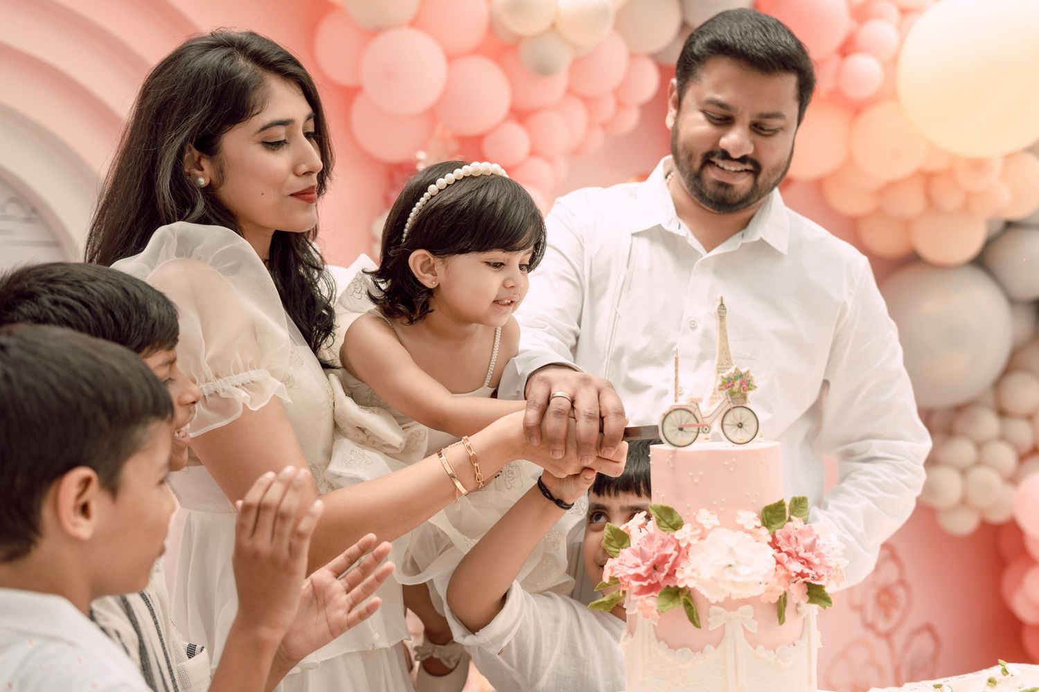 Family celebration with pink balloon arch backdrop and festive decor.