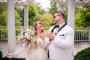 A joyful wedding moment captured under a white pergola with string lights and columns.