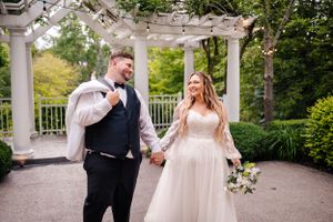 A candid wedding moment captured under a pergola with string lights in a garden setting.